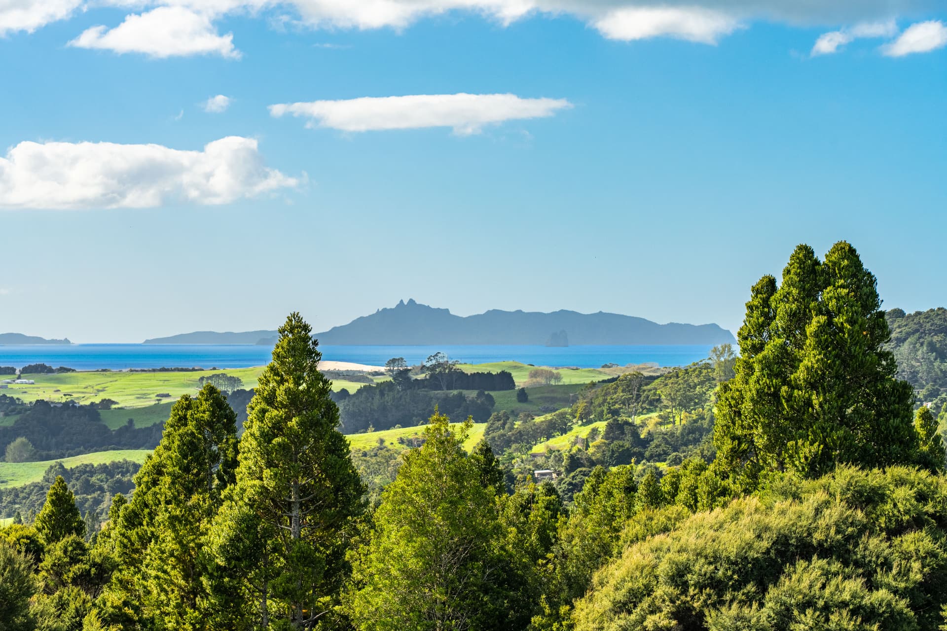 Mangawhai coastal landscape with green hills, turquoise sea and distant islands